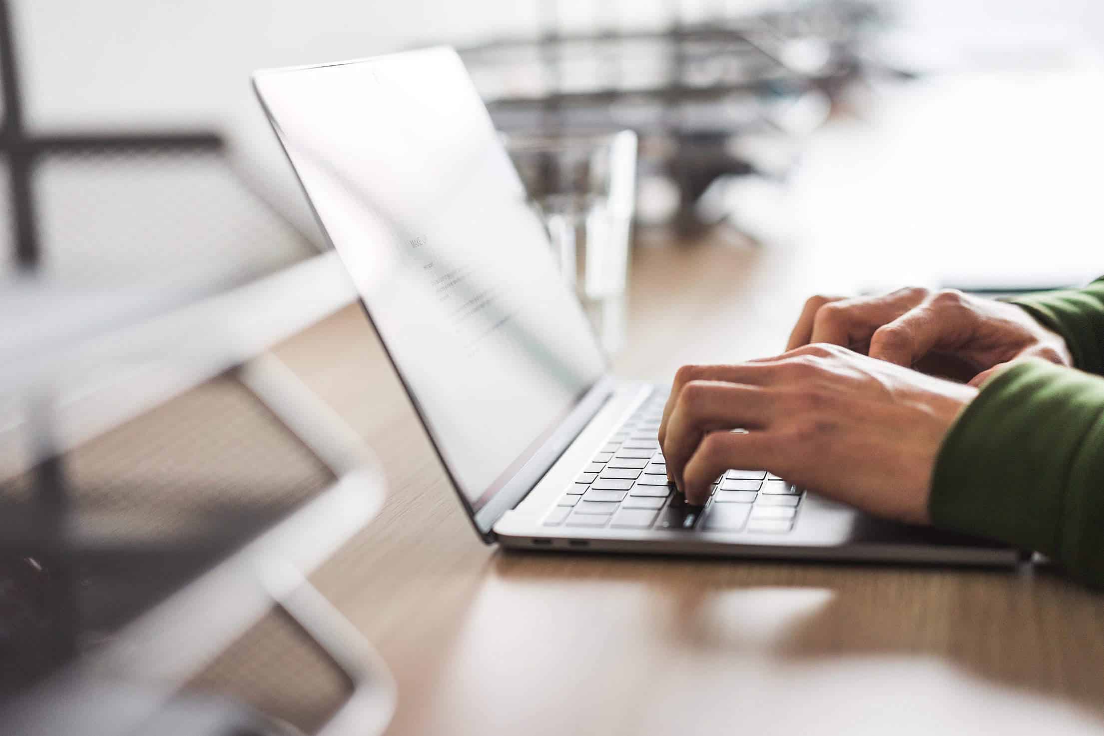 Hands typing copy on a laptop